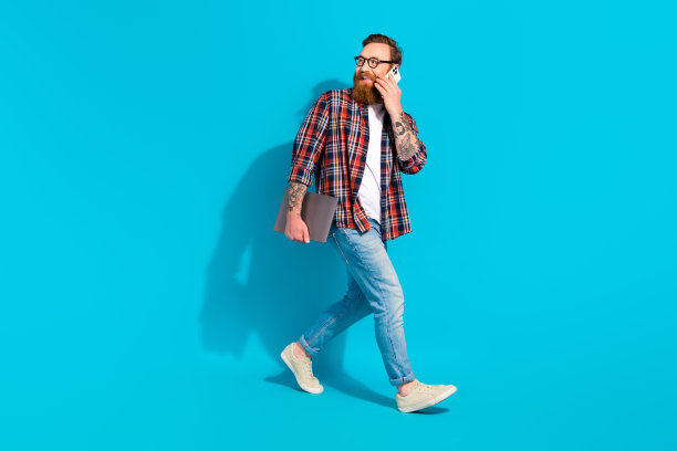 步骤的全身照片，年轻的商业工作者带着上网本打电话给他的团队领导，看起来在蓝色背景上孤立的模型图片下载