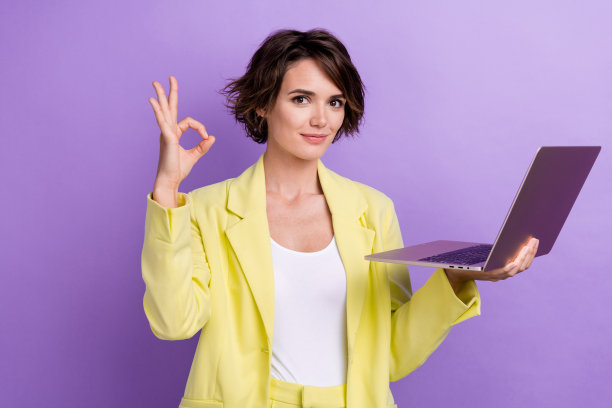 好的女士鲍勃的照片棕色的头发穿石灰时尚的西装魅力装拿笔记本电脑电子商务交易孤立在紫色的背景图片下载