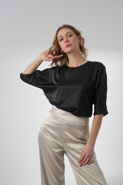 一系列的工作室照片的年轻女模特穿着简单美丽的服装，丝绸缎面黑色衬衫和白色阔腿裤图片下载