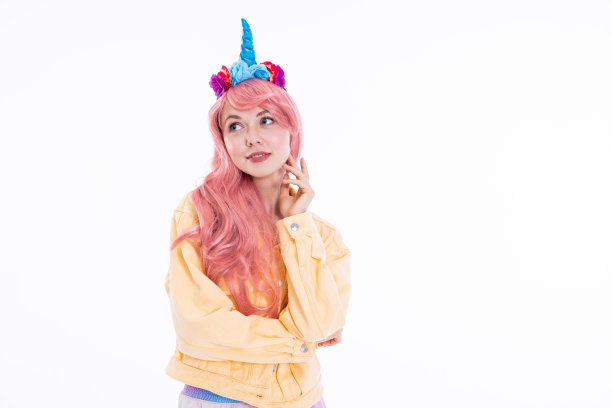 照片中间的年轻女子戴着独角兽蓝色发带和粉红色假发，在拍摄过程中摆姿势，心情很好图片下载