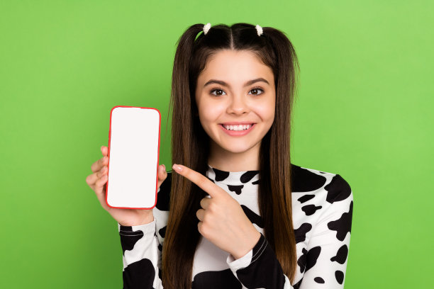 时髦积极的女士穿着牛皮衬衫指向现代装置空白空间孤立的绿色背景的照片图片下载