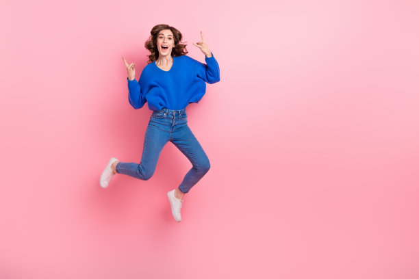 粗心的人跳跃手臂手指的全长照片展示了重金属符号空白的空间孤立在粉红色的背景图片下载