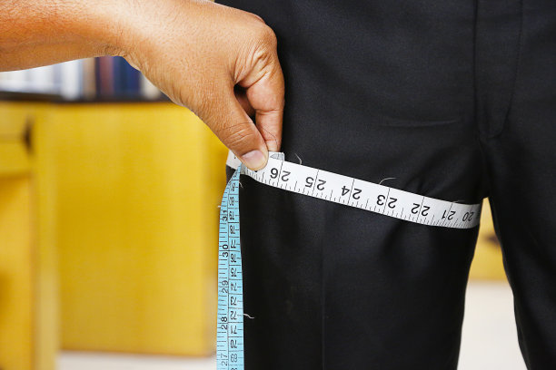 裁缝用卷尺测量男子大腿的特写图片下载