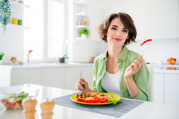 照片相当积极的女士坐在椅子厨房桌子吃自制的盘子叉子拿辣椒片现代公寓室内图片下载