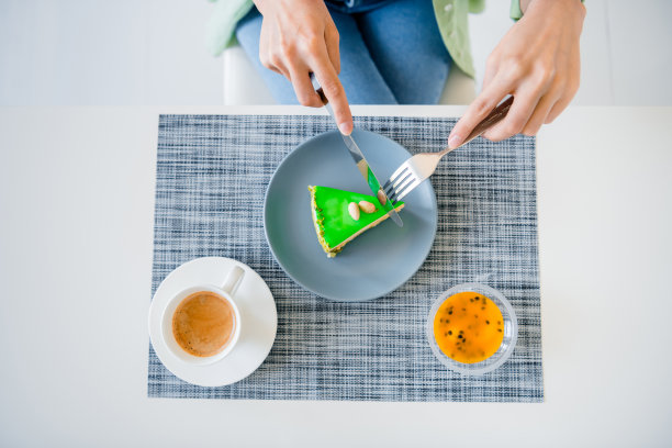 俯视图照片，年轻的女士手臂切绿色水果蛋糕在室内厨房图片下载