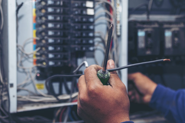 电气机械技术员检查电气柜的电线。检验员手操作配电盘机械维修服务。电工电路维修电压操作。男人双手修理断路器图片下载