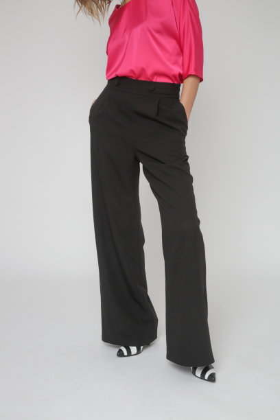 一系列的工作室照片，年轻的女模特穿着简单漂亮的衣服，丝绸缎粉色衬衫和黑色阔腿裤图片下载