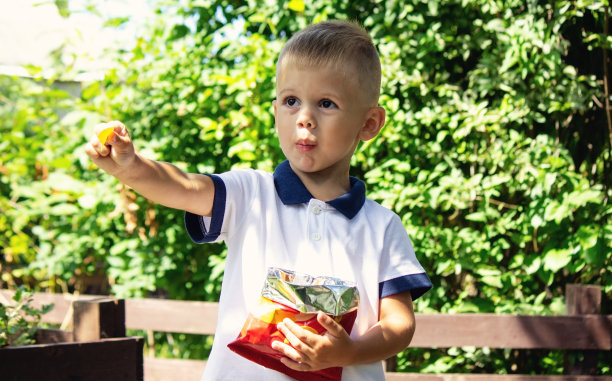 一个男孩在公园里吃薯片。有选择性的重点图片下载