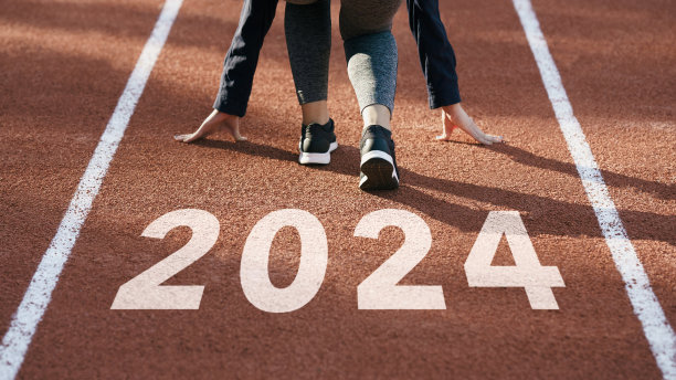 2024年新年快乐象征着新的一年的开始。一名男子准备在刻有2024年字样的田径跑道上跑步的后视图。成功的目标。准备迎接新的一年图片下载