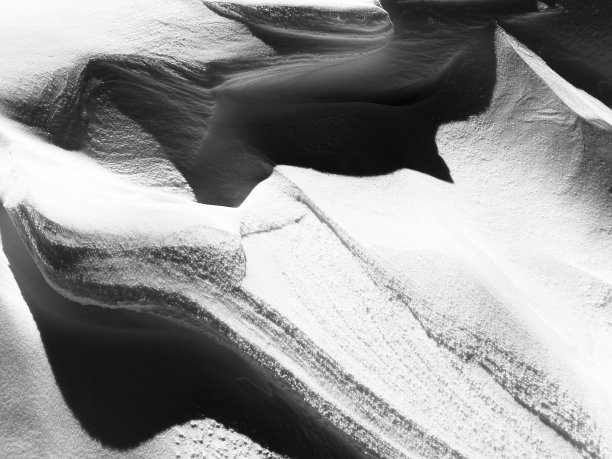 山上的风在雪中形成抽象的图案。图片下载