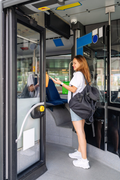 都市年轻女子在电动穿梭巴士内用手机付车费的照片。公共交通移动支付。图片下载