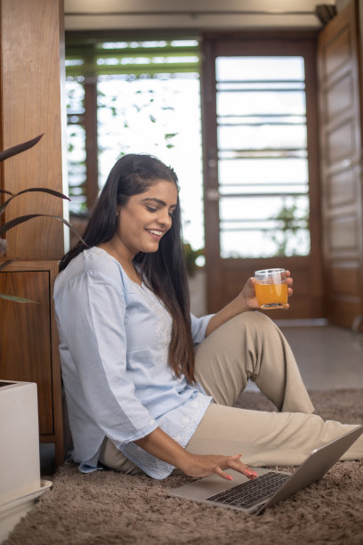 女人在家里的地毯上使用笔记本电脑图片下载