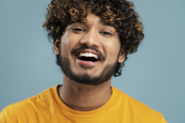 照片中，一个满脸微笑、留着大胡子的印度男人，他的妆容自然自然，被孤立在背景中。护肤美容图片下载