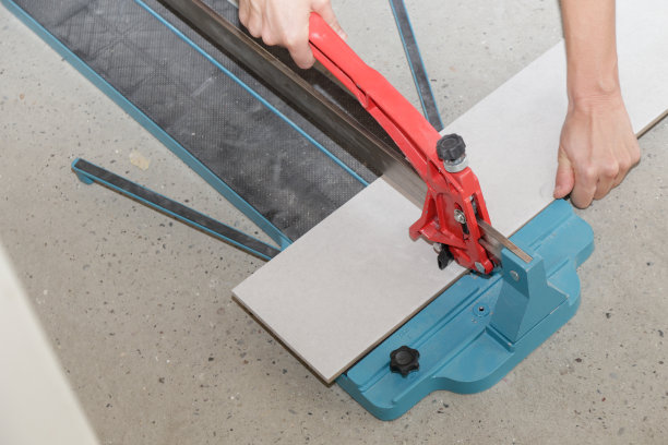 使用标准的手动瓷砖切割机切割瓷砖。瓷砖在浴室中逐步安装的过程。DIY家居装修。图片下载