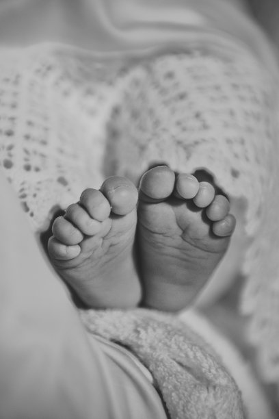 婴儿的腿。宝宝的脚。可爱的小睡觉和躺在家里的床上。特写镜头。刚出生的小男孩或小女孩的光脚裹在柔软舒适的毯子里。前视图。黑白照片。图片下载