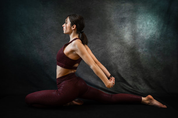 穿着红色运动服的白人苗条女孩在黑色工作室背景下做早晨伸展运动图片下载