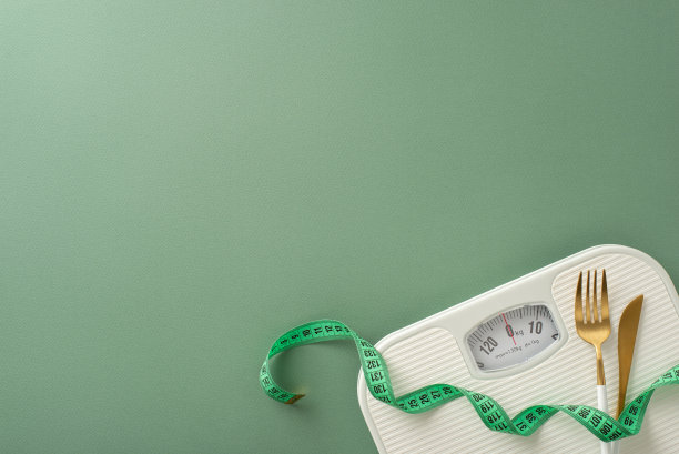 健康和身体改造主题。俯视图照片展示地板尺度，卷尺，叉和刀在绿色设置，理想的文字或广告图片下载