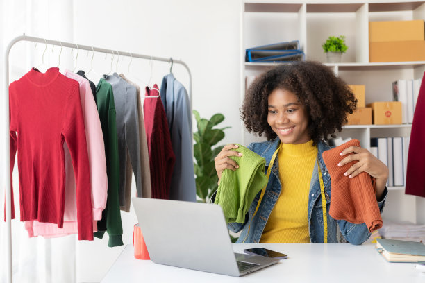 非裔美国女孩在网上通过直播赠送和销售服装，选择一家时尚的服装店。时装设计师绘制新系列的图片。图片下载