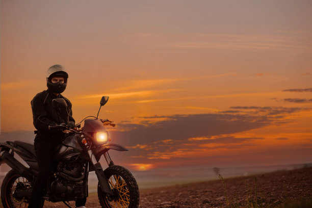 一个摩托车手的剪影在日落与耐力摩托车，概念的浪漫摩托车生活。图片下载