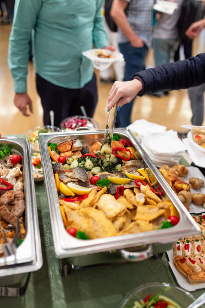 男子从暖盘里舀海鲜。健康餐自助午餐。图片下载