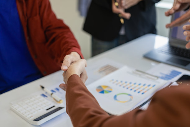 快乐的商人握手，在会议上提出建议，在办公室的桌子上，拿着图表，拿着金融文件。建议合同。经理和顾客握手。特写照片图片下载