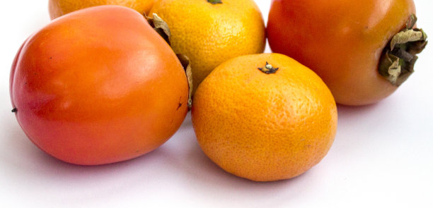 橘子和柿子的特写照片被隔离在白色的背景上图片下载