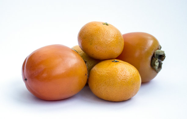 橘子和柿子的特写照片被隔离在白色的背景上。图片下载