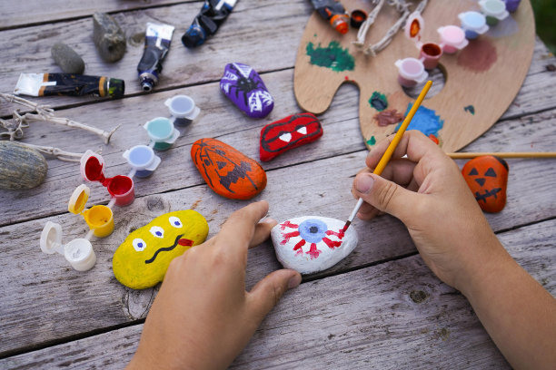Diy的概念。一个孩子的手在石头上画万圣节人物的详细图片。儿童艺术项目。聚会装饰。图片下载