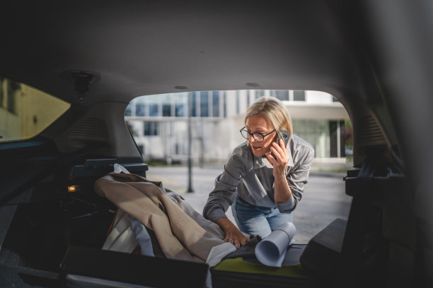 成熟的金发女子旅行时从汽车后座拿东西图片下载