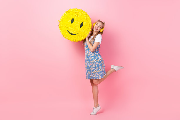 一个非常开朗的人的全长照片，听音乐，耳机拿着大的笑脸表情，在粉红色的背景上拼贴出来图片下载