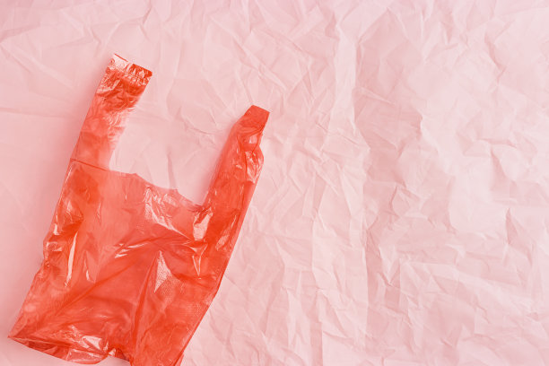 无塑料概念，俯视图皱巴巴的塑料袋皱巴巴的粉红色皱纸背景，复制空间。一次性聚乙烯食品包装。生态趋势最小的风格照片，红色单色图片下载
