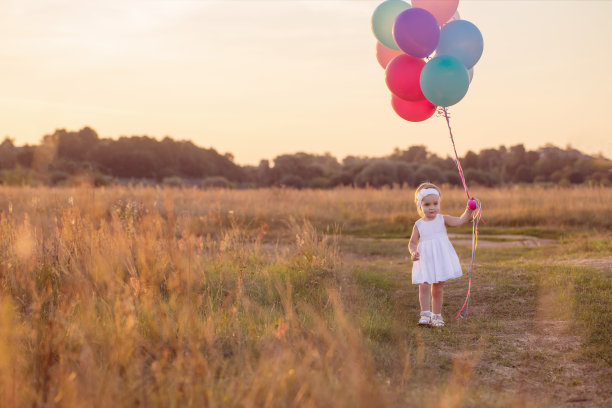 穿着白色衣服的小女孩在户外拿着气球图片下载