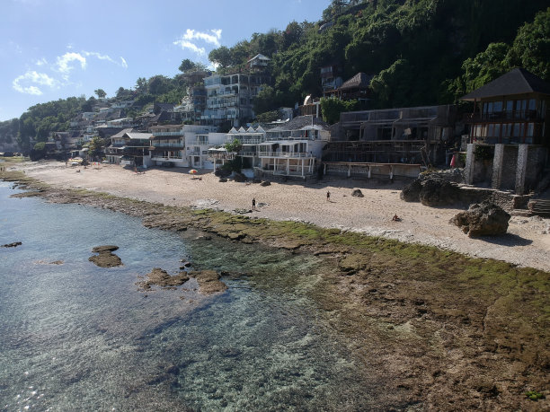 2023年8月，一个阳光明媚的日子，在退潮期间，无人机在巴厘岛乌鲁瓦图的宾金海滩拍摄的照片，周围有餐馆、房子和人们图片下载