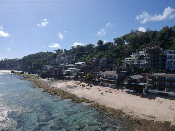 2023年8月，一个阳光明媚的日子，在退潮期间，无人机在巴厘岛乌鲁瓦图的宾金海滩拍摄的照片，周围有餐馆、房子和人们图片下载