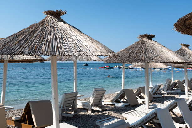 沙滩上有遮阳伞的日光浴床，用于出版，设计，海报，日历，帖子，屏幕保护程序，壁纸，明信片，横幅，封面，网站。高质量照片图片下载