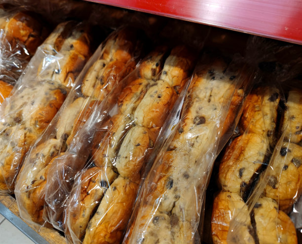 一袋袋用塑料袋包裹着的葡萄干面包放在超市面包店的货架上，准备出售图片下载