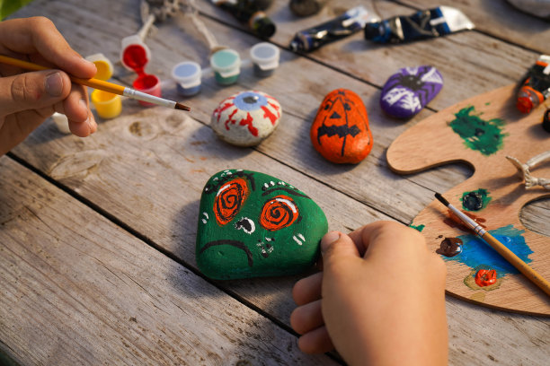 Diy的概念。一个孩子的手在石头上画万圣节人物的详细图片。儿童艺术项目。聚会装饰。图片下载