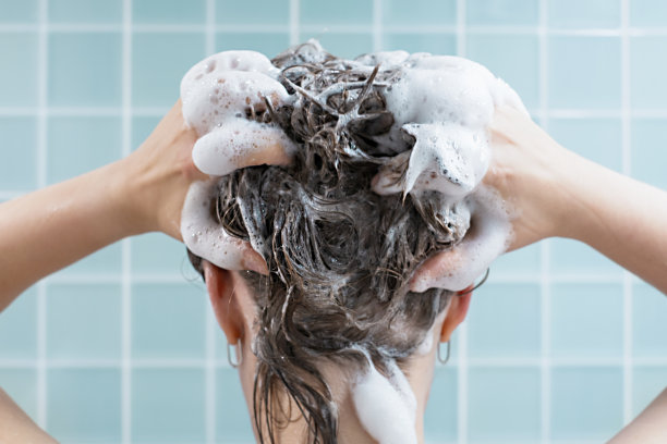 女孩用洗发水洗头，蓝色背景，后视图图片下载