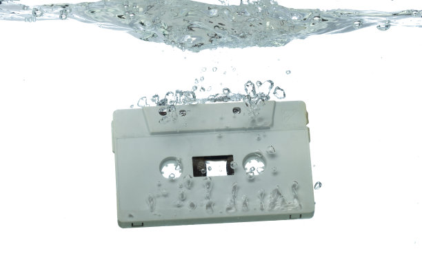 盒式复古磁带落入带有气泡的清水中。黑色复古复古盒式磁带滴洗旧时光。白色背景隔离冷冻元件图片下载