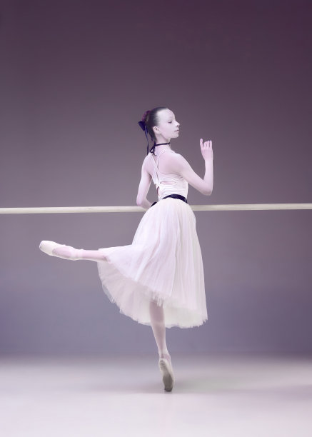 感激的表演者，年轻女子，专业芭蕾舞演员，穿着可爱的裙子，在工作室背景上用巴棍指着图片下载