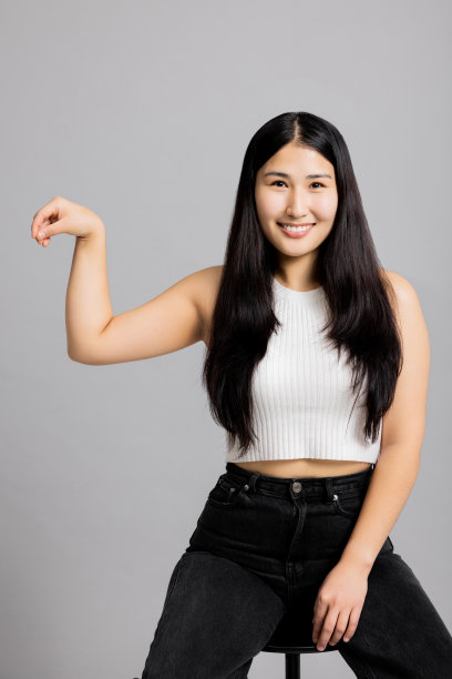 空白快乐的亚洲泰国日本女人站在灰色背景的工作室孤立穿着白色t恤举起手拿着东西展示广告图片下载