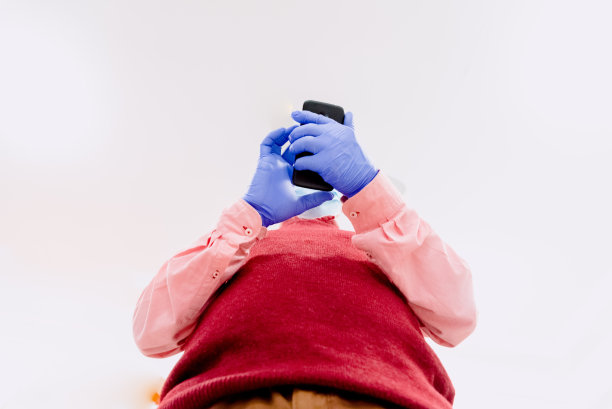 戴乳胶手套的男子在摆弄他的手机。图片下载