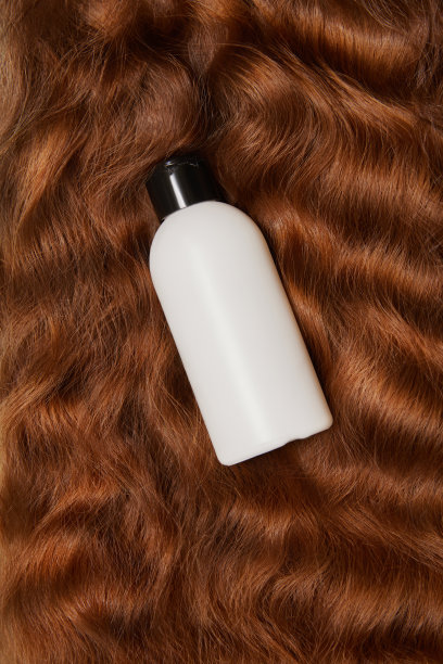 一瓶洗发水的照片，护发素在波浪柔滑光泽的长黑发。俯视图，平铺。副本的空间。自我护理，头发护理。图片下载