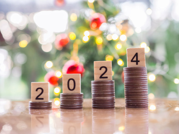 木块编号2024上叠硬币与圣诞灯散景背景。圣诞快乐，新年快乐，省钱的概念为2024年的新年做准备。图片下载