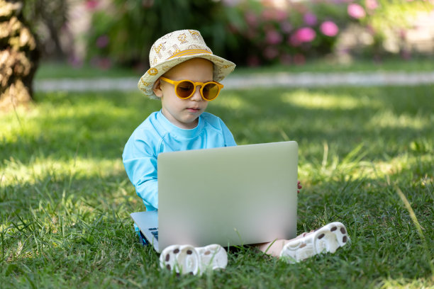 小男孩双手放在电脑键盘上，看着笔记本电脑屏幕。孩子和科技度假的概念。图片下载