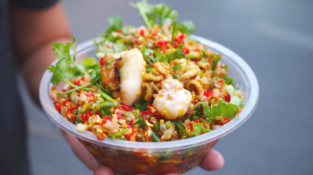 图为泰式烤鱿鱼手握，吃辣海鲜蘸酱。泰国街头小吃的照片图片下载