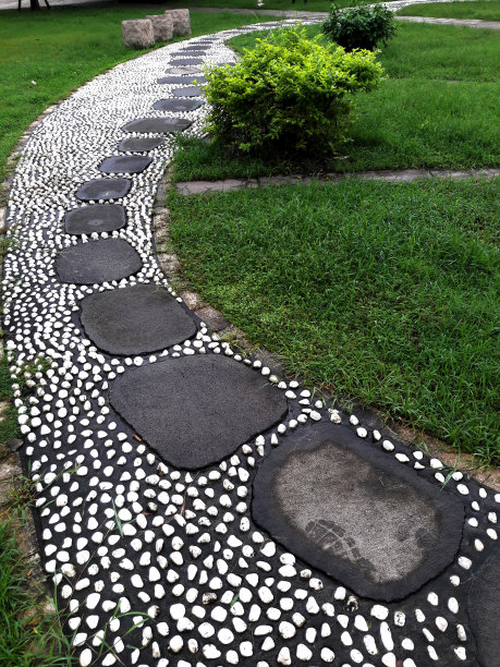 公园景观。白鹅卵石和黑石头组成了一条人行道。石头的道路。公园的道路。石头的道路。园林绿化，特写照片图片下载