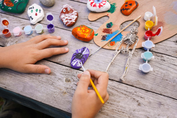 Diy的概念。一个孩子的手在石头上画万圣节人物的详细图片。儿童艺术项目。聚会装饰。图片下载