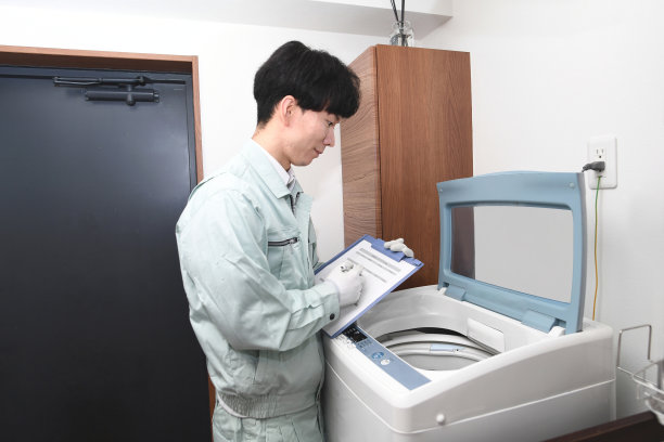 穿着工作服的亚洲男性工人正在检查家用洗衣机图片下载