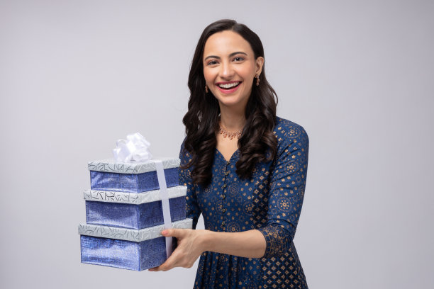 美丽的印度妇女穿着传统服装，拿着礼盒庆祝排灯节，孤立在白色背景的股票照片图片下载